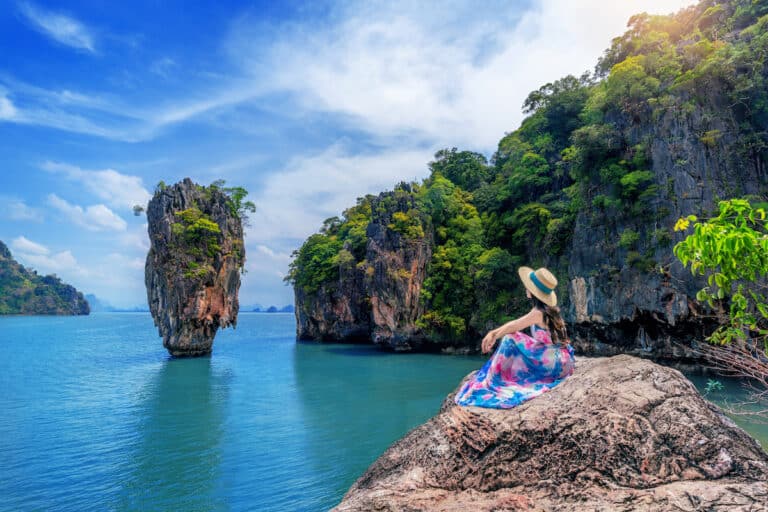 Beautiful girl sitting on the rock at James Bond island in Phang nga, Thailand.